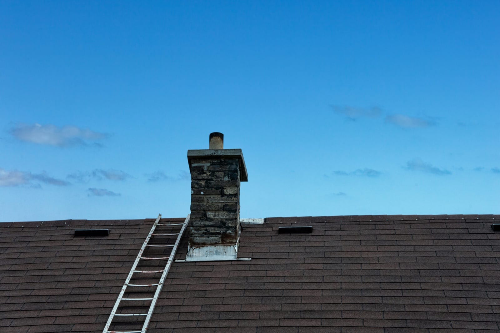 Roofing crew installing new shingles on a residential pitched roof on a clear morning